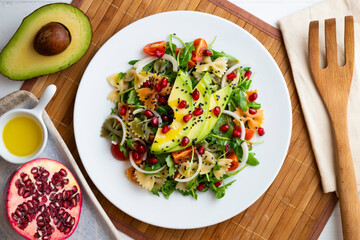 Argula salad with pasta bows, avocado, cherry tomatoes, pomegranate and sesame.