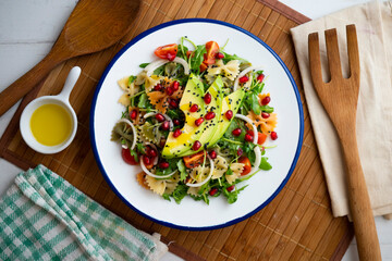 Argula salad with pasta bows, avocado, cherry tomatoes, pomegranate and sesame.