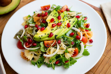 Argula salad with pasta bows, avocado, cherry tomatoes, pomegranate and sesame.