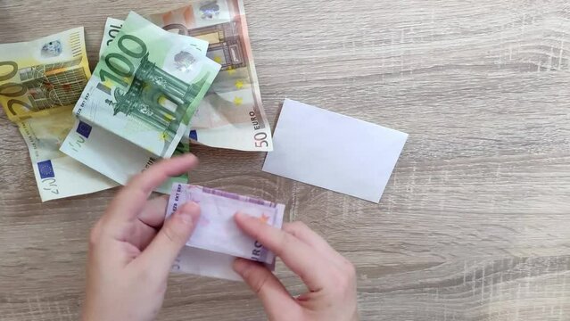 mujer coge billete de quinientos euros y lo guardarlo en un sobre de papel. Video 4K UHD.
