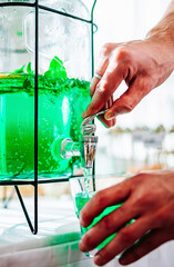 hands pour lemonade from a bottle into a glass