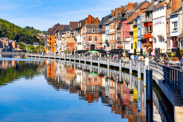 Fototapeta na wymiar Dinant, Belgium. View on street with typical traditional colorful houses on the river Meuse against blue sky