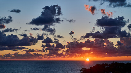 Sunset with dramatic clouds over the sea. and the sun is narrowing beyond the horizon, panoramic view 