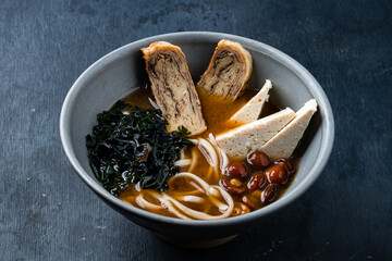 Asian vegetarian ramen noodle soup close-up with roasted tofu cheese and shiitake mushrooms in a bowl