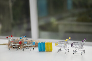 Miniature shopping cart on wooden mock up over blurred green garden on day noon light, Image for...