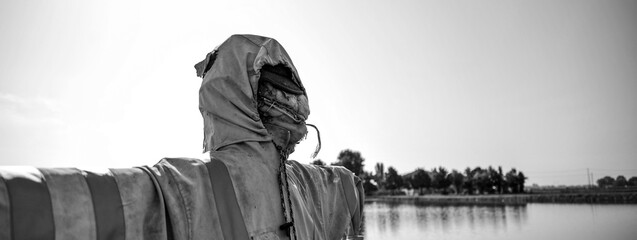 Horizontal banner or header with real scarecrow with fearful face in front of the lake - Halloween...