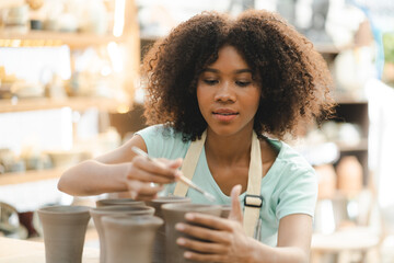 Creative afro American young woman artist molding clay on pottery wheel, Workshop in ceramic...