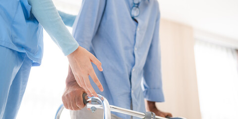 Portrait of Asian young nurse helping old elderly disable man grandfather to walk by using walker...