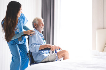 Obraz premium Full length portrait of Asian young female nurse assisting old senior man in wheelchair to looking at retirement home, carrying about disabled grey haired man in wheelchair, health insurance concept