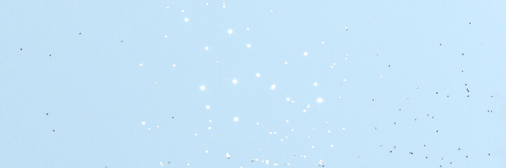 Sparkling silver glitter on blue background banner texture. Abstract holiday blurred lights header. Wide screen wallpaper. Panoramic web banner with copy space for design