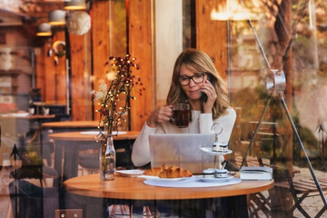 Attractive businesswoman using laptop and smartphone while working in a cafe