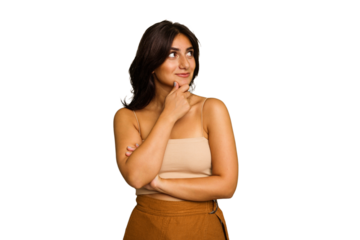 Young Indian woman isolated on green chroma background looking sideways with doubtful and skeptical expression.