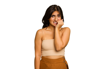 Young Indian woman isolated on green chroma background biting fingernails, nervous and very anxious.