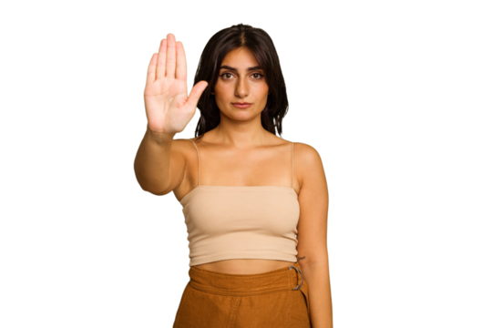 Young Indian woman isolated on green chroma background standing with outstretched hand showing stop sign, preventing you.