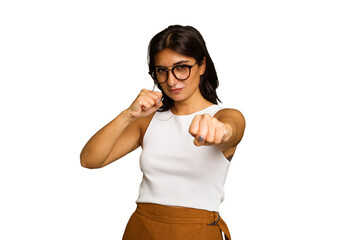 Young Indian woman isolated on green chroma background throwing a punch, anger, fighting due to an...