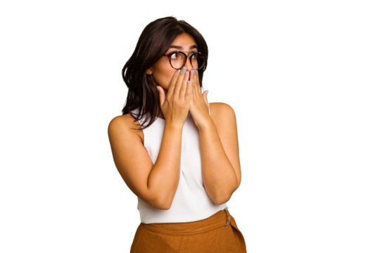 Young Indian woman isolated on green chroma background thoughtful looking to a copy space covering mouth with hand.