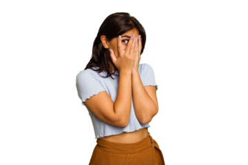 Young Indian woman isolated on green chroma background blink through fingers frightened and nervous.