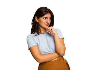 Young Indian woman isolated on green chroma background confused, feels doubtful and unsure.