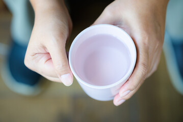 Closeup woman holding a cup of water with two hands, going to drink a cold water