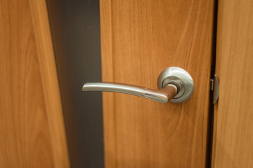 Silver handle on a wooden door with glass. Interior door with a gray metal knob