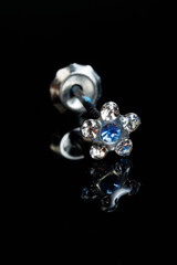 Jewelry with stone earrings, luxury silver earrings with diamonds, sapphires on a black background.