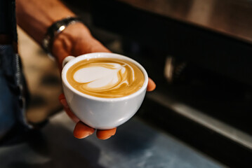 Barista hand hold cup cappuccino Coffee with espresso and milk in cafe