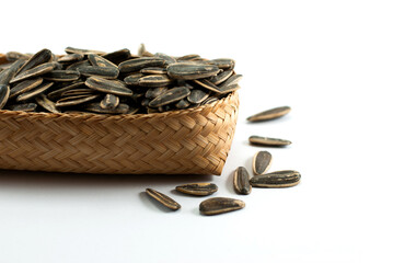 Sunflower seeds are placed in a wicker container and put on a white background.