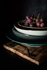 Red grapes in a retro plate on a dark background. Rustic atmosphere. Creative idea.