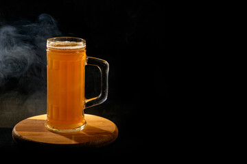 A glass of beer in the backlight , isolated on black smoke background . With space for text 
