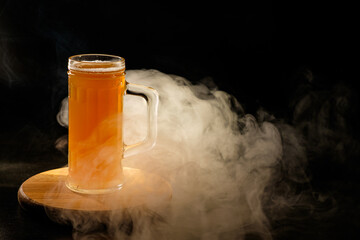 A glass of beer in the backlight , isolated on black smoke background . With space for text 