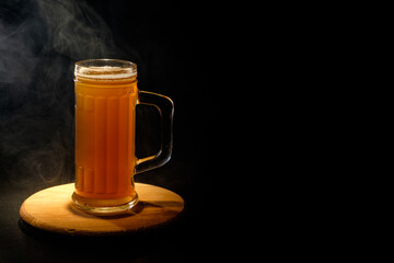 A glass of beer in the backlight , isolated on black smoke background . With space for text 