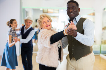 Elderly woman learning ballroom dancing in pair in dance studio