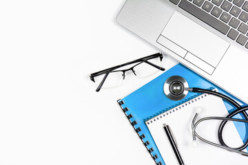 Laptop, notepad with pen, glasses and stethoscope on white background