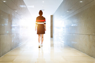 Woman walking down a corridor towards lit exit