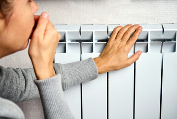 Woman warming her hands on the heater, close-up