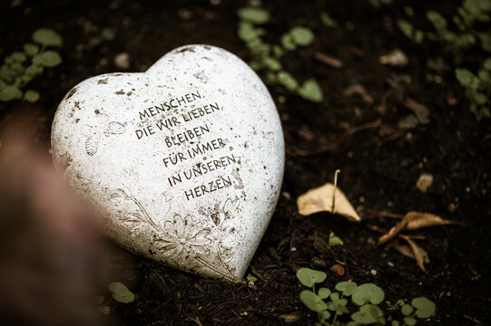Herz auf Grab mit Inschrift "Menschen, die wir lieben, bleiben für immer in unseren Herzen"
