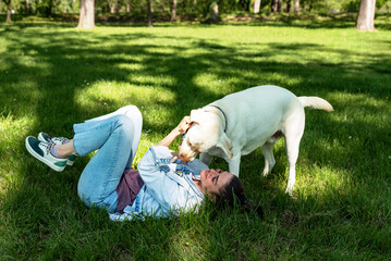 Young woman adopt young dog Labrador Retriever from animal rescue center and gave him love and friendship. Female animal lover spending time with her puppy in the park.