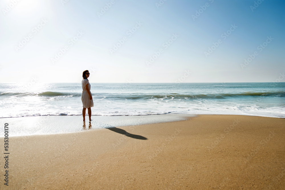 Wall mural young asian woman relaxing on the beach at sunrise.