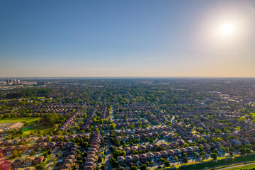 Aerial view of rich American citizen’s suburb at golden hour summertime. Established Real estate view of wealthy residential houses near greenery, parks and trees.