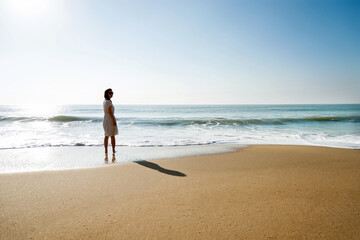 Young asian woman relaxing on the beach at sunrise.