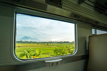 Riding a train in Indonesia sitting by the window watching the tracks and the view outside the window of the train speeding towards its destination