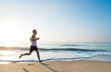 Young man running along beach  in the morning
