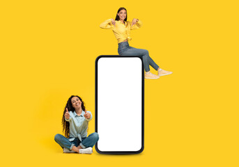 Happy european young woman sit on phone, have fun, show thumbs on big smartphone with blank screen
