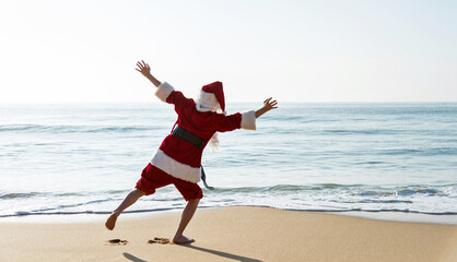 Obraz premium Santa claus standing on beach with arms outstretched.