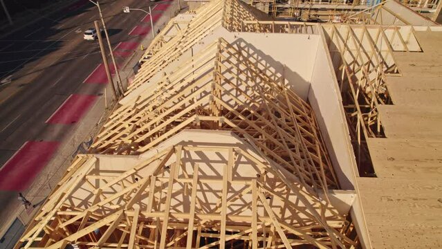 Housing gables roof on wood sticks. Wooden city home under construction at golden hour. New downtown building roof with wooden truss beam framework.