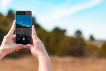 Woman's hands taking a photograph of the landscape with a smartphone.
