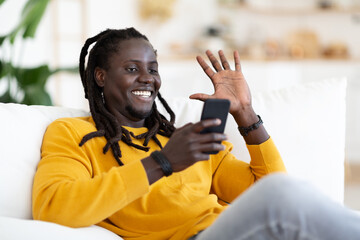 Distant Communication. Smiling Black Guy Making Video Call Via Smartphone At Home