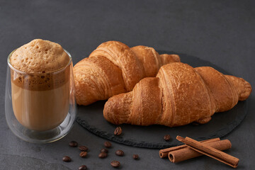 Croissants with cinnamon and coffee on a dark stone table. French breakfast. Composition for advertising and menus of cafes and restaurants