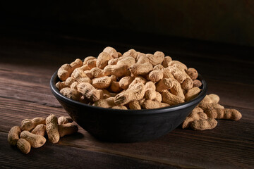 Dried peanuts in a bowl on a wooden table.