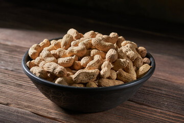 Dried peanuts in a bowl on a wooden table.